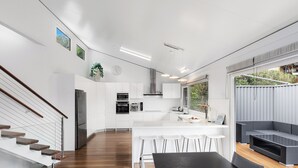 Una cocina moderna con armarios blancos, un refrigerador de acero inoxidable y una isla grande con taburetes de bar.