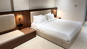 Una habitación de hotel moderna con una cama grande, mesitas de noche e iluminación empotrada.