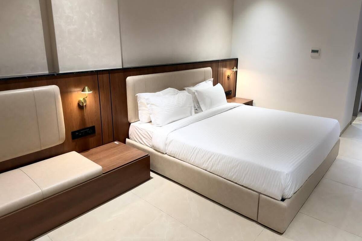 A modern hotel room with a large bed, bedside tables, and built-in lighting.