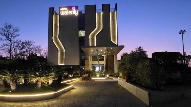 Un hotel moderno con una entrada destacada, un camino bien iluminado y un jardín ajardinado.