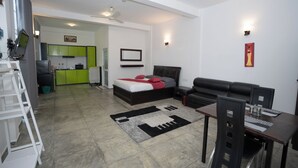 A modern living room with a bed, a dining table, and a kitchen in the background. - Hotel Ranthil - Galle (Galle)