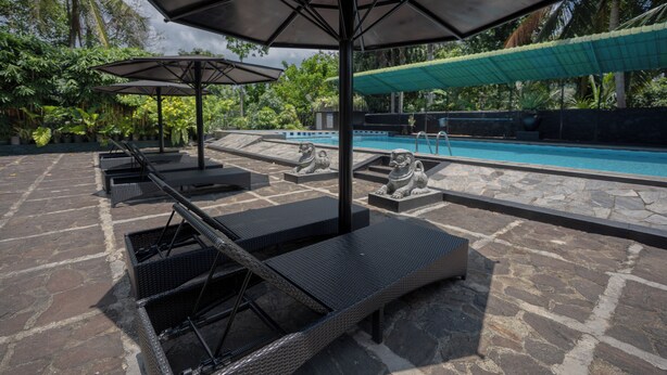 A poolside area with lounge chairs, umbrellas, and stone flooring. - Hotel Ranthil - Galle (Galle)