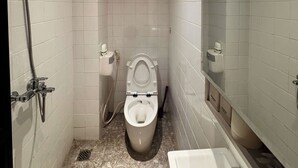 A small, modern bathroom with white tiles, a toilet, a shower, and a bathtub. - Best Location | Home Cinema | Peaceful | Calmigo (Thành phố Hồ Chí Minh)