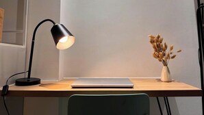 A desk with a laptop, a black desk lamp, and a vase with dried plants. - Best Location | Home Cinema | Peaceful | Calmigo (Thành phố Hồ Chí Minh)