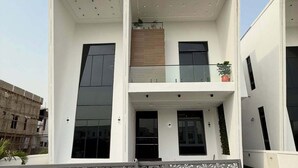Un bâtiment moderne à deux étages, doté d’un balcon, de grandes fenêtres et d’une clôture en métal décorative.