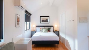 Une chambre à coucher avec un lit, des tables de chevet, une fenêtre et une porte.