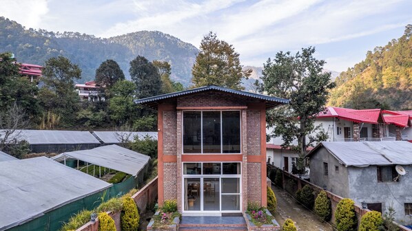 A two-story building with a brick facade, large windows, and a small garden area. - Casa Gaula By ELIVAAS Spanish Theme 4BHK (Bhowali Range)