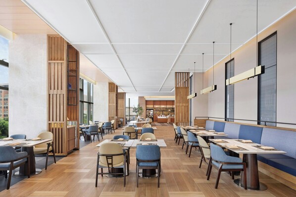 A spacious restaurant with high ceilings, modern furniture, and large windows.