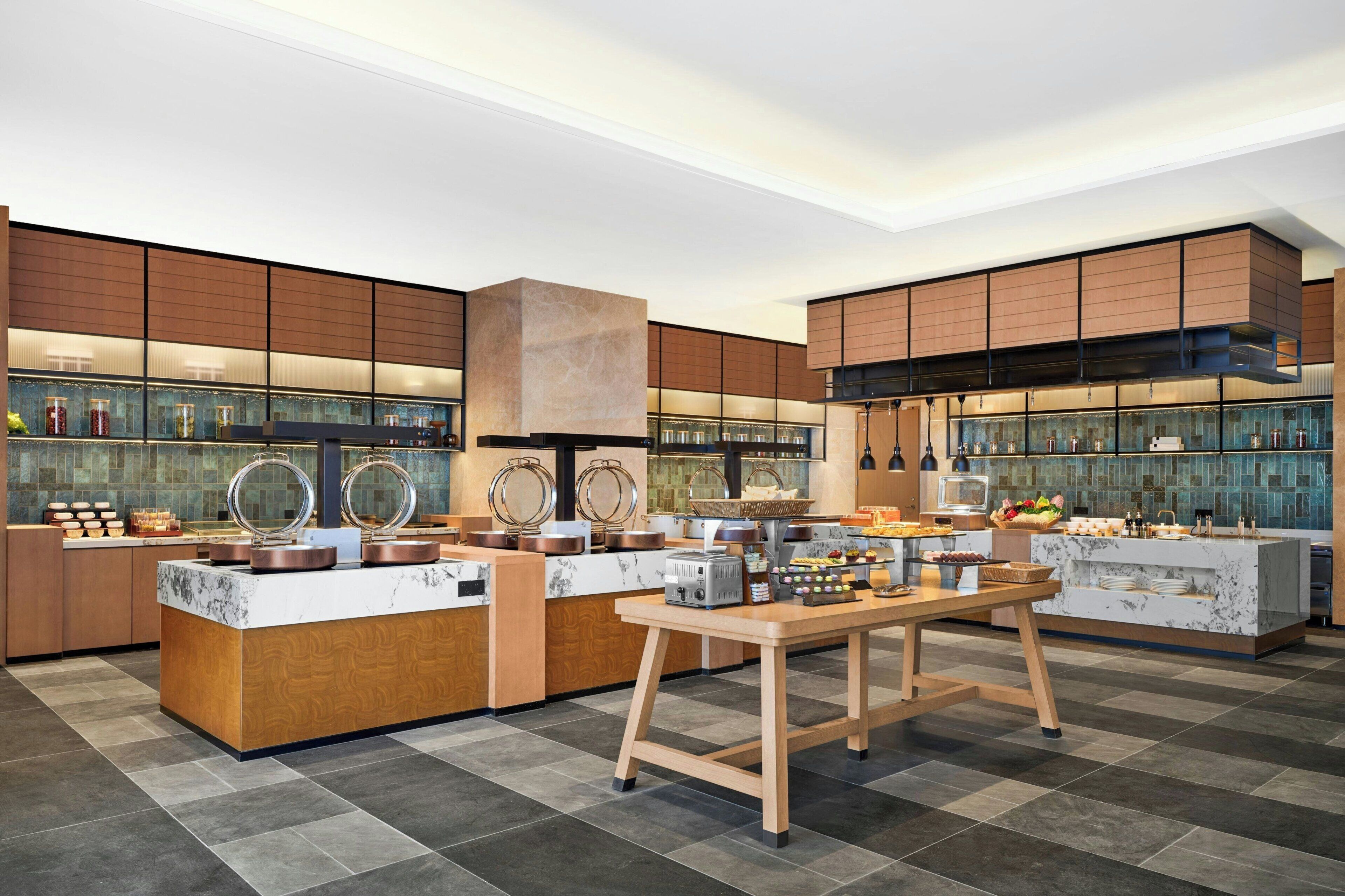 Una cocina moderna con encimeras de mármol, armarios de madera y una isla central con cafetera.