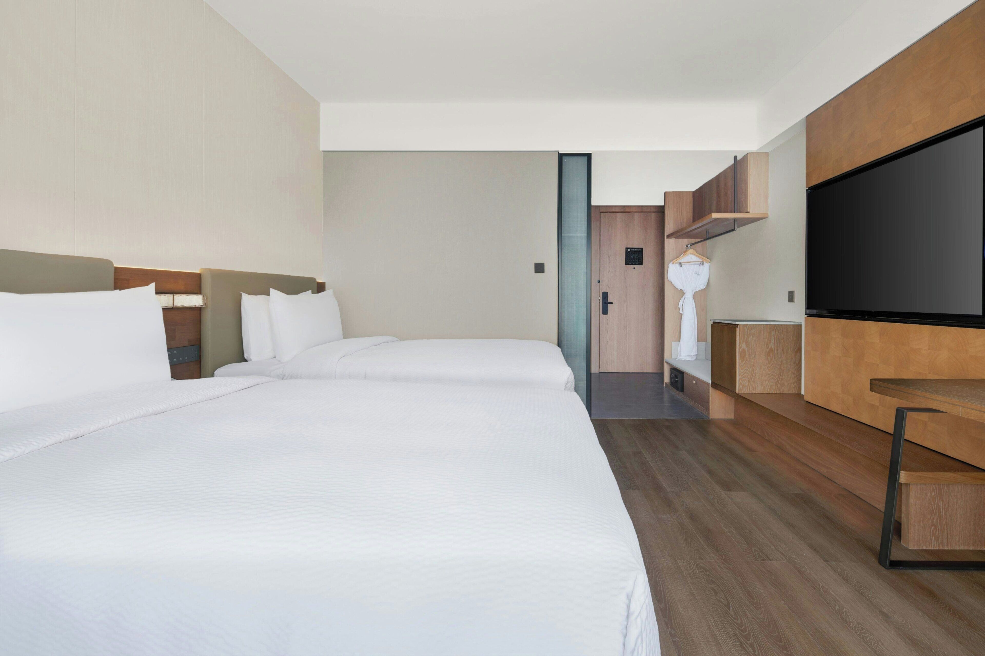 Ein Hotelzimmer mit zwei Betten, einem Fernseher und einem Holzschrank.