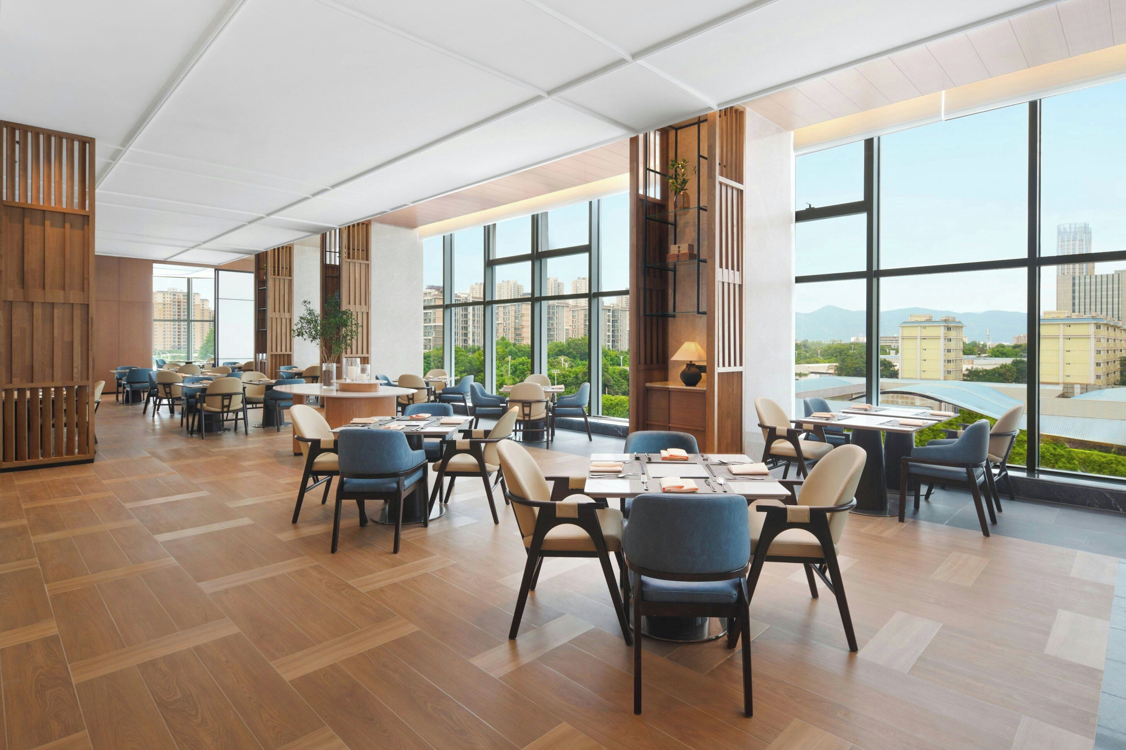 Un restaurante espacioso con techos altos, ventanas amplias y una decoración de estilo moderno.