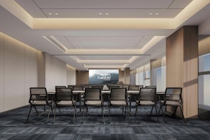 A conference room with a long table, chairs, and a large screen.