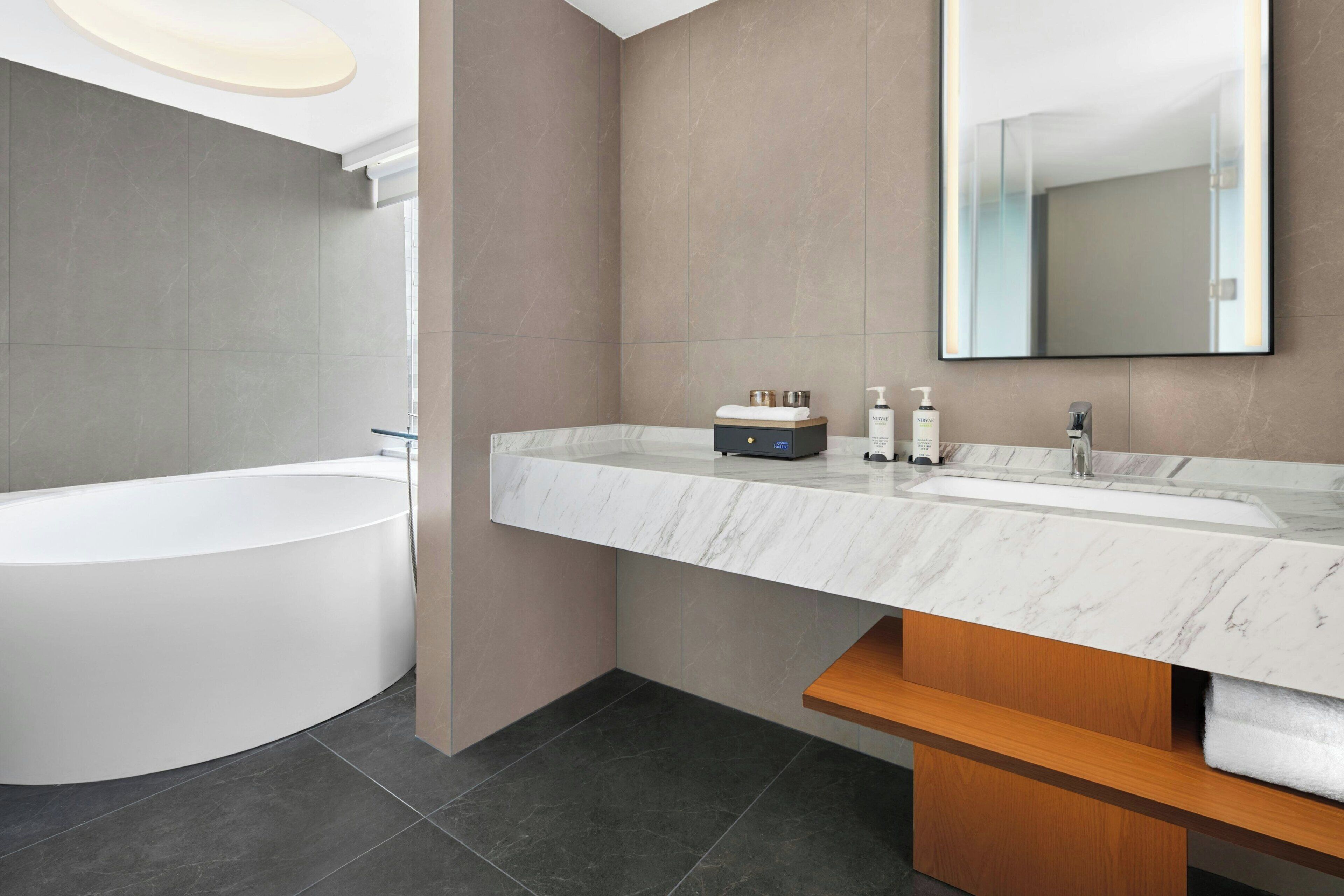 Une salle de bain moderne avec une baignoire sur pieds, un meuble-lavabo en marbre et un grand miroir.