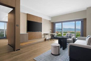 A modern hotel room with a large TV, a desk, a sofa, and a view of the city. - Fairfield by Marriott Kunming Xishan (Kunming)