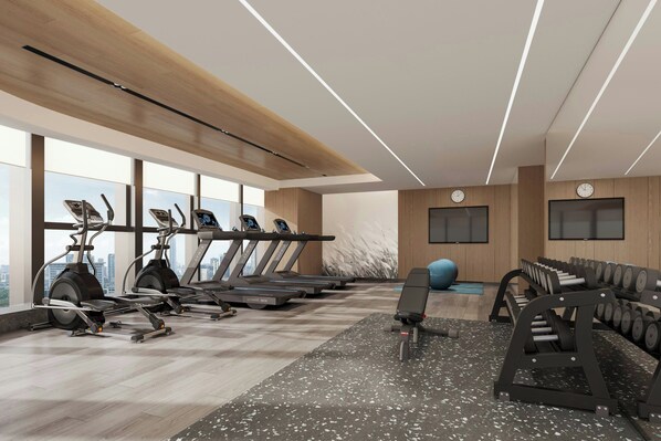 A gym with treadmills, weight machines, and a large window with a city view.