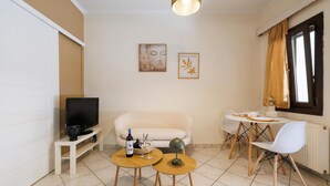 A living room with a TV, sofa, two small tables, and a dining area with chairs. - Apartment 'Breathing  1' with Mountain View, Wi-Fi and Air Conditioning (Virós)