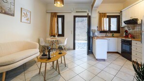 A living room with a sofa, a dining table with chairs, a kitchen with white cabinets, and a pendant light. - Apartment 'Breathing  1' with Mountain View, Wi-Fi and Air Conditioning (Virós)