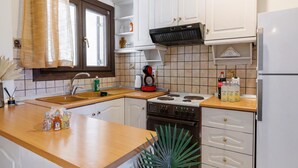 A kitchen with white cabinets, a wooden countertop, a stove, a sink, and a window with a curtain. - Apartment 'Breathing  1' with Mountain View, Wi-Fi and Air Conditioning (Virós)