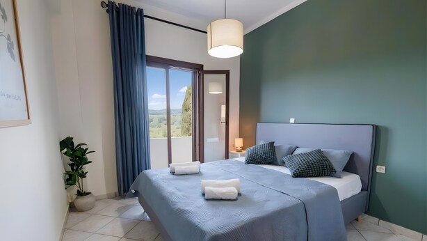 Une chambre à coucher avec un lit, une plante en pot, une vue par la fenêtre et un luminaire suspendu.