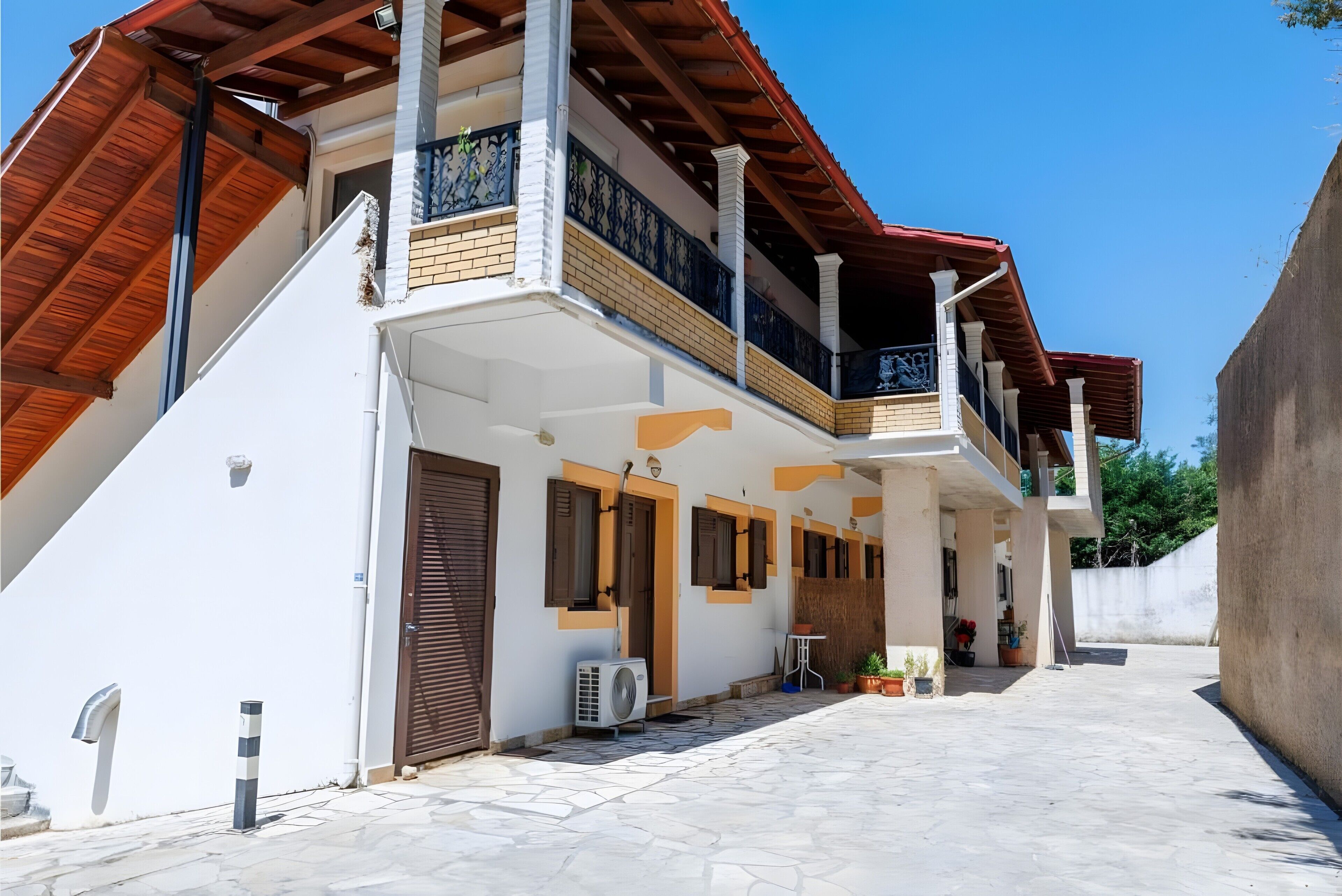 A two-story building with a covered balcony, a tiled entrance, and a small outdoor seating area.