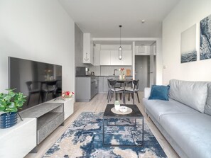A modern living room with a grey sofa, a coffee table, and a TV. - Apartment in Niechorze by Baltic Beach (Rewal)