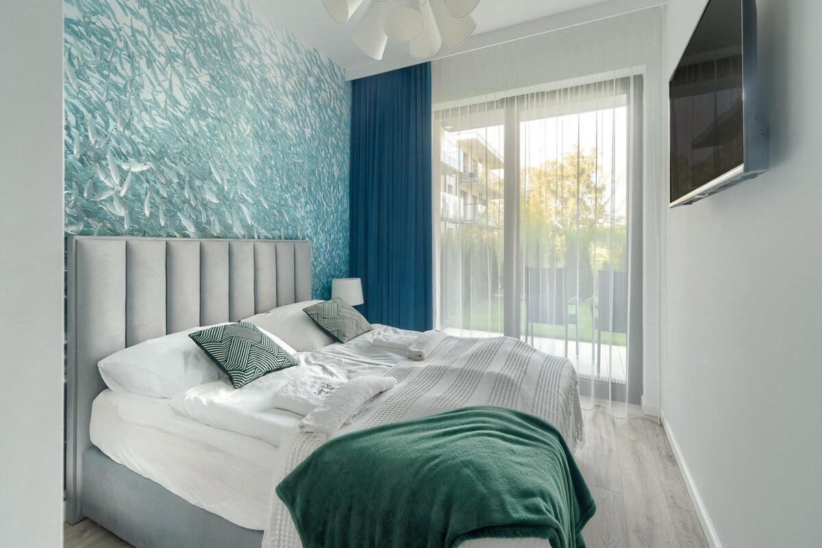 Ein modernes Schlafzimmer mit einem großen Bett, Blick ins Freie und einer einzigartigen Wandkunst.
