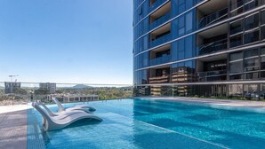A modern building with a rooftop pool featuring a unique wave-like edge design. - Lovely Sunny 2-bedroom Apartment With Pool and Gym (Canberra)