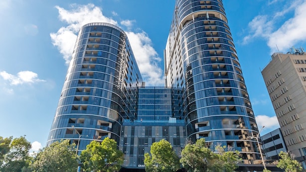 A modern high-rise building with a curved facade, multiple balconies, and a glass entrance. - Lovely Sunny 2-bedroom Apartment With Pool and Gym (Canberra)