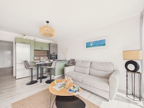 A modern living room with a sofa, a coffee table, and a dining area with chairs. - Apartment for 3, 100m from the beach (St-Brévin-l’Océan)