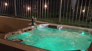 Un bain à remous à l’intérieur bleu clair, entouré d’une clôture métallique agrémentée de lumières.
