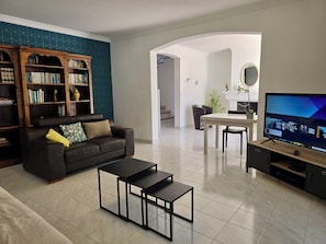 A living room with a sofa, coffee table, TV, bookshelf, and a dining area with a table and chairs. - Villa Joseli /Private pool/6 guests (Oletta)