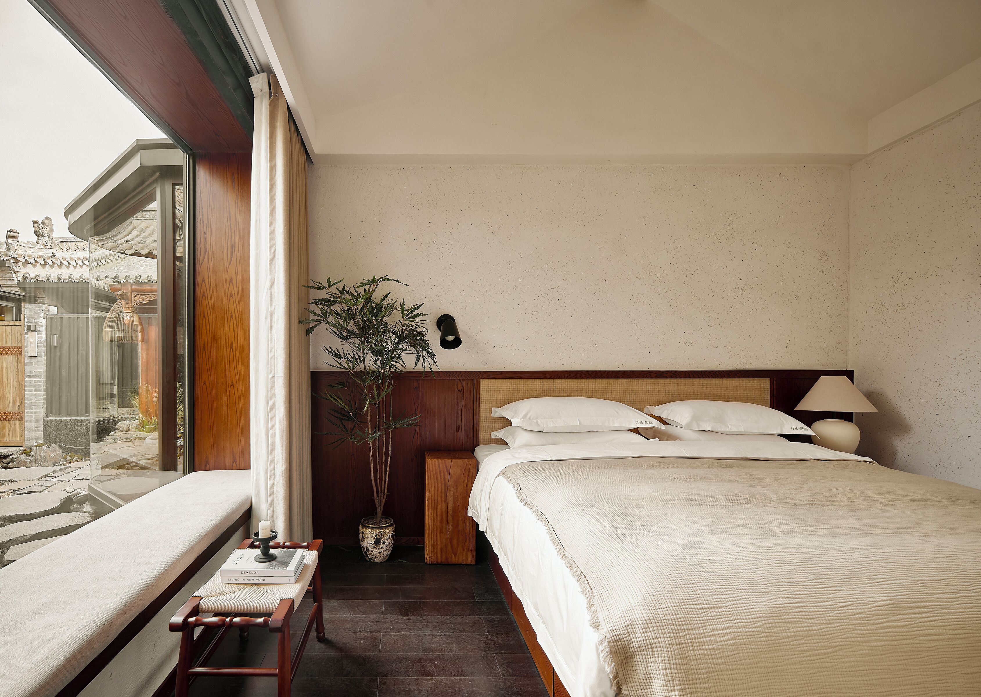 Habitación de hotel con cama, mesita de noche, lámpara y vistas a un edificio tradicional.