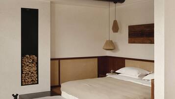 A bedroom with a bed, bedside table, lamp, and a wall-mounted shelf with logs.