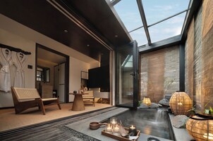 A modern spa with a glass-enclosed hot tub, wooden furniture, and ambient lighting.