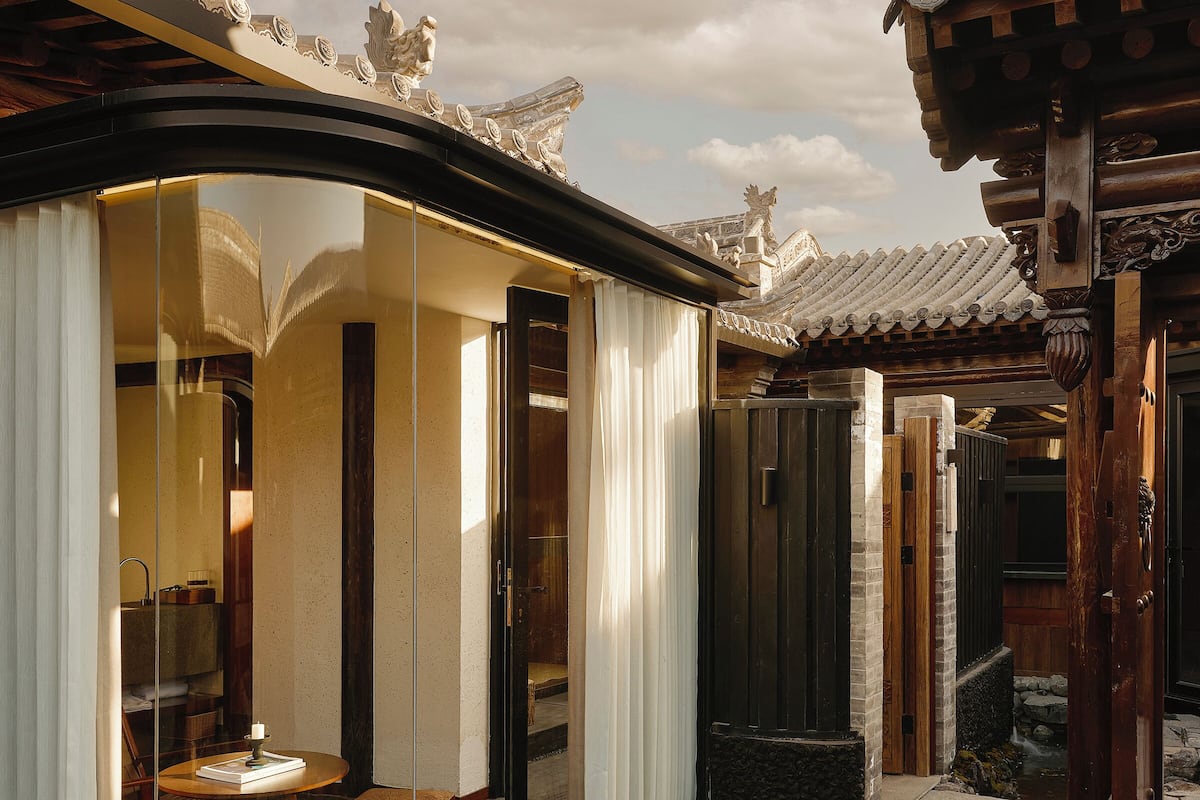 A traditional building with a curved roof, a small water feature, and a wooden table with a candle.