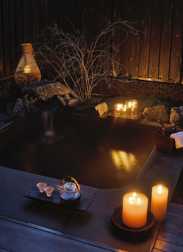 A serene outdoor setting with a hot tub, candles, and a lantern. - XINGYUN TANGYIN (Datong)