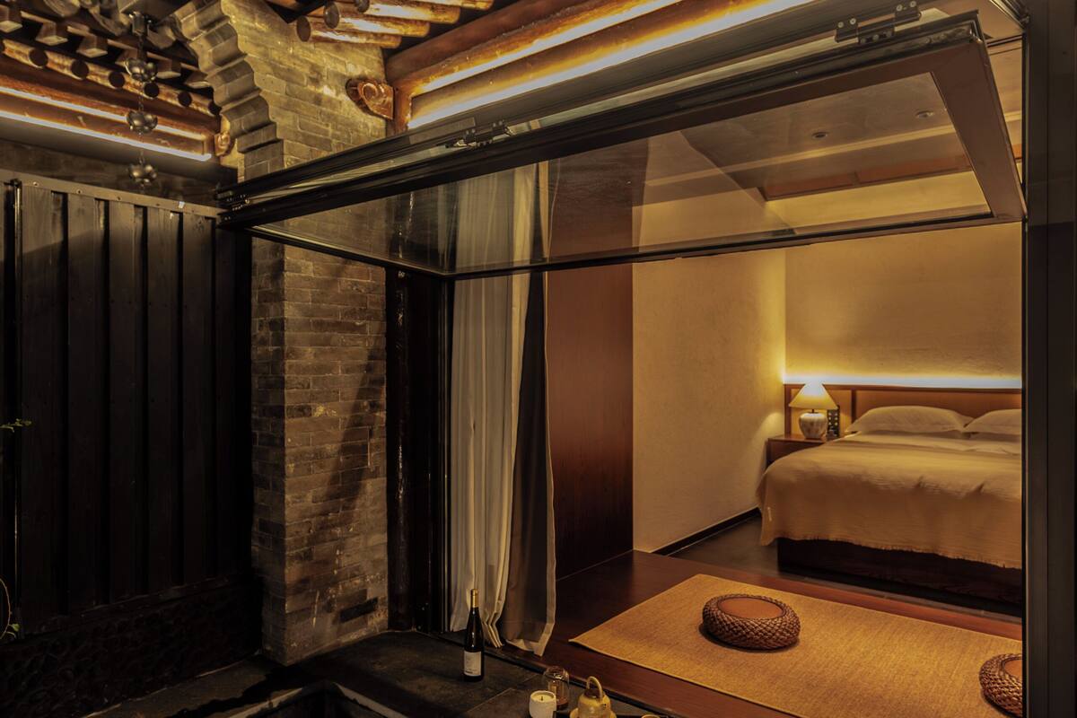 A modern hotel room with a large window, a bathtub, and a neatly made bed.