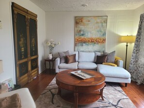 A living room with a sofa, a coffee table, a painting, and a lamp. - Serene and Comfortable Suburban Hideaway (Lower Sackville)