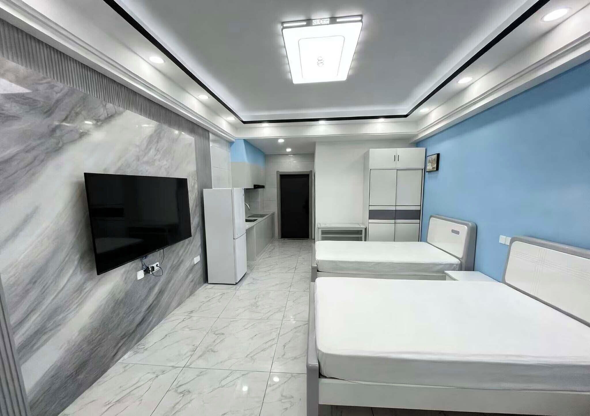 Een moderne hotelkamer met een flatscreen televisie, twee bedden, een kledingkast en een badkamer.