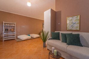 Uma sala de estar moderna com sofá, almofadas, mesa lateral, estante e uma obra de arte pendurada na parede.