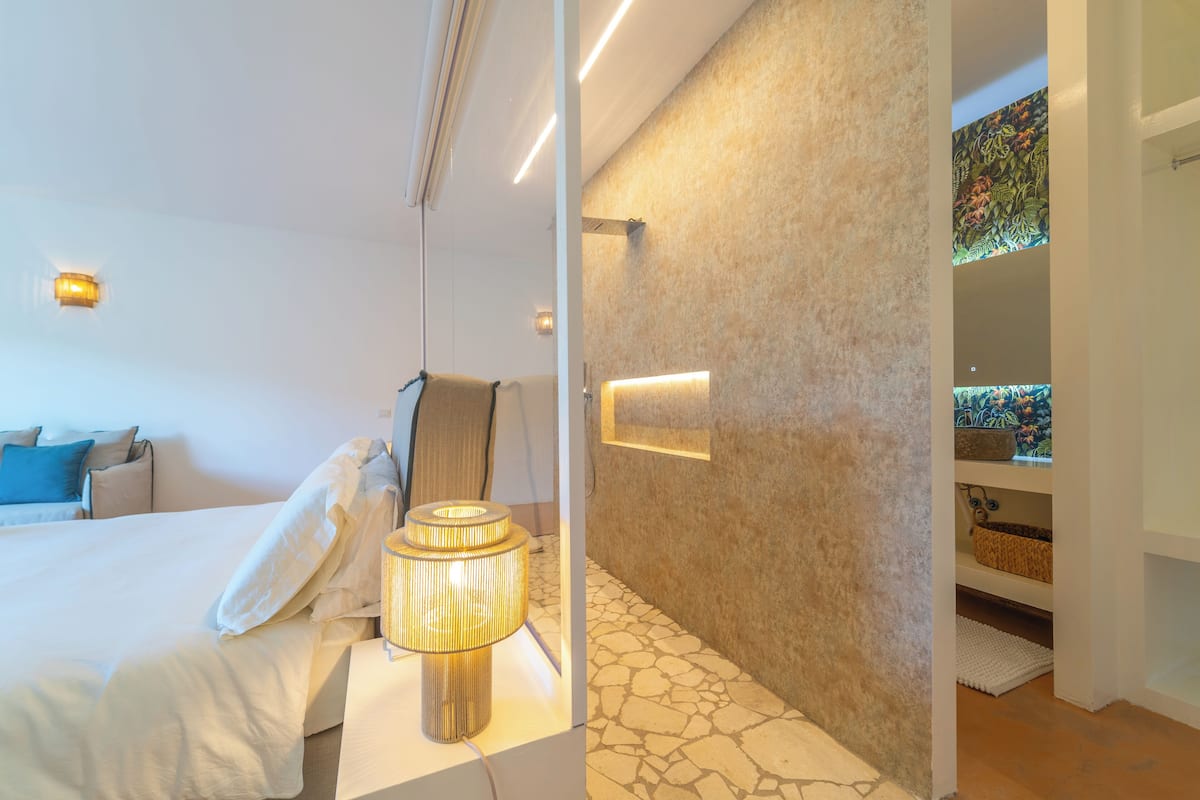 Una habitación de hotel moderna con cama, lámpara de noche y un detalle decorativo en la pared.