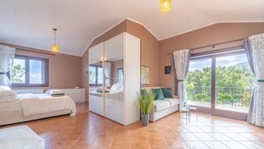Un dormitorio con cama, sofá, mesita, planta en maceta y balcón con vistas.