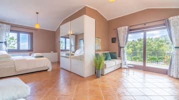 Un dormitorio con cama, sofá, mesita, planta en maceta y balcón con vistas.