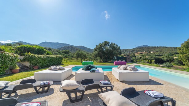 Un área junto a la piscina con sillones de descanso y piscina.