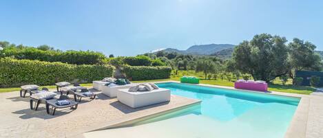 A swimming pool with lounge chairs and a stone patio.