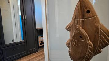 Ein Zimmer mit einem dunklen Holzschrank, einem weißen, flauschigen Teppich und einer Holz-Fischdekoration an der Wand.