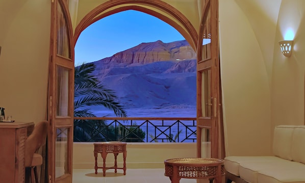A room with a large arched window, a small table, a sofa, and a decorative wall light.