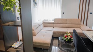 Una sala de estar moderna con un sofá modular, una mesa de centro con flores y un control remoto en el suelo.