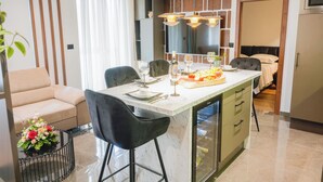 Una cocina moderna con una isla central, taburetes de bar y un comedor con sofá y mesa.