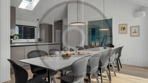 Un'area pranzo moderna con un tavolo lungo, sedie nere e lampade a sospensione.